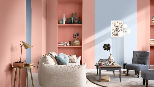 Woonkamerinterieur met roze planken, lichtgekleurde fauteuil, bijzettafel, lamp en illustratieve wanddecoratie