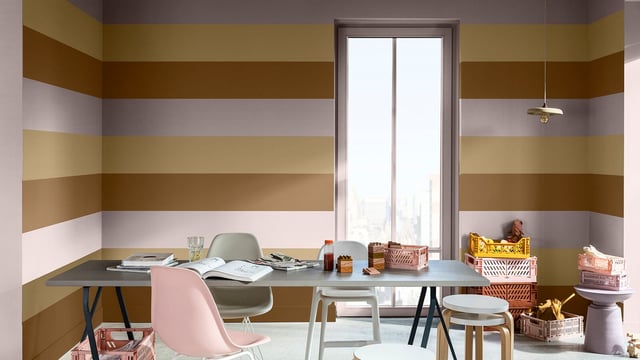 Modern thuiswerkplek met kleurrijke strepen op de muur, bureau bij het raam en stoelen.