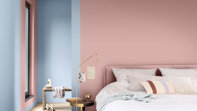 Moderne slaapkamer met roze muren, opgemaakt bed met gestreepte kussens, nachtlampje en raamlicht