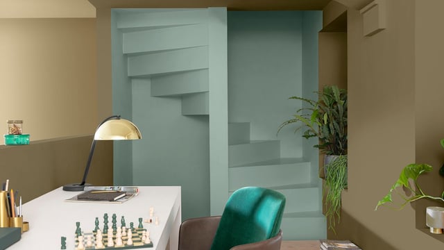 Stijlvol thuiskantoor met turquoise stoel, bureau en vloerlamp, met planken en planten