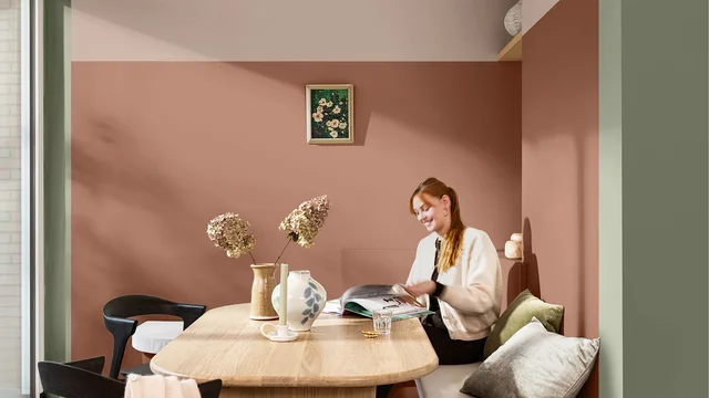 Vrouw werkt aan een bureau in een gezellige thuiswerkruimte met roze muur.