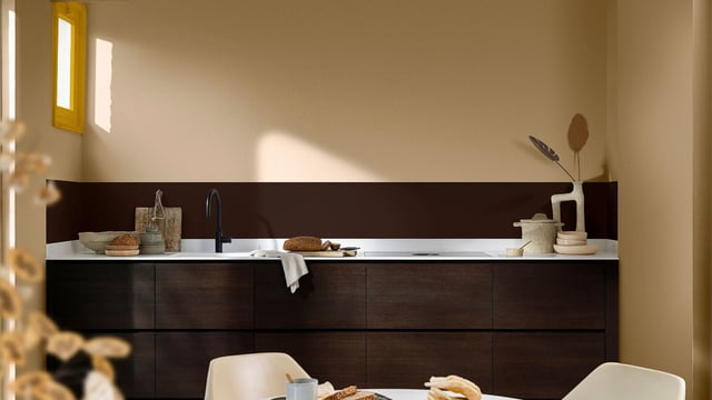 Moderne keuken met donkere kasten, spoelbak en een gedekte tafel met eten en servies.