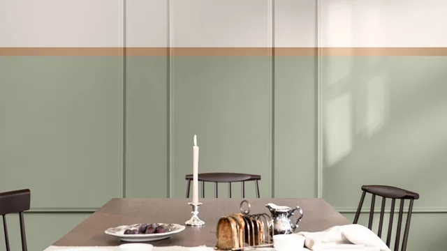 Een rustige eettafel in een thuiskantoor met een brandende kaars en drie houten stoelen tegen een saliegroene muur.