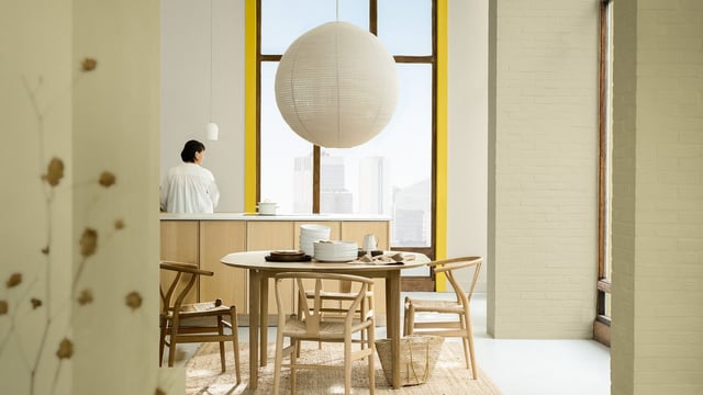 Lichte moderne keuken/eetruimte met tafel bij het raam, ronde lamp en stoelen.