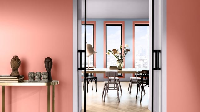 Modern interieur met roze- perzik wandplank en decoratieve vazen, zicht op een lichte eetruimte met bloemen.
