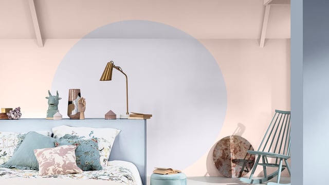 Lichte slaapkamer met blauw bed, decoratieve plank, vloerlamp en schommelstoel bij een ronde muurvorm