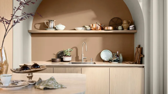 Stijlvolle keuken met ingebouwde plank en werkblad, servies en koperen pannen