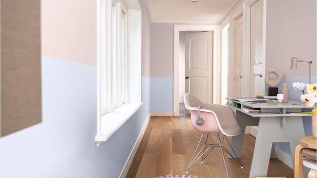 Licht thuiswerkkantoor: roze stoel, wit bureau en bloemen in een pastelblauwe ruimte.