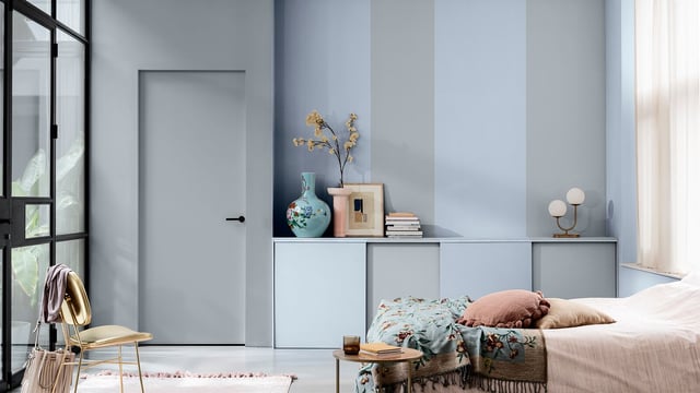 Lichte slaapkamer met een eenpersoonsbed, blauwe decoratie, vaas met takken en planken tegen lichtblauwe muren