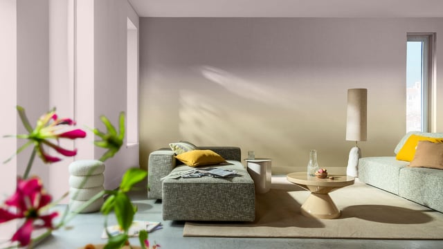 Smaakvol ingerichte woonkamer met bank, ronde salontafel en vloerlamp bij de ramen.