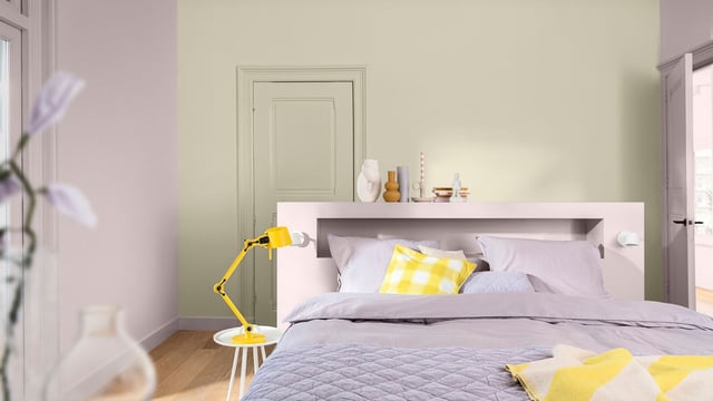 Lichte slaapkamer met bed, gele decoratie en een vloerlamp.