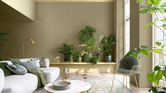 Moderne woonkamer met beige bank, marmeren salontafel en groene planten bij grote ramen