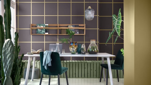 Modern thuiswerkplek met wit bureau, groene stoelen, paarse rasterwand en planten in potten.