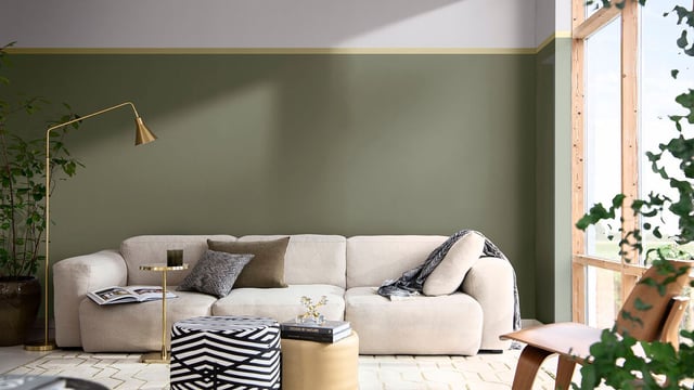 Moderne woonkamer met lichtgroene muur, witte bank, bijzettafel, vloerlamp en groot raam.