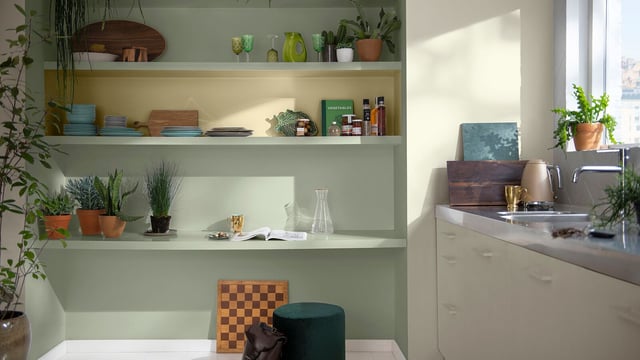 Lichte keuken met witte planken, groene decoratie en planten bij de spoelbak
