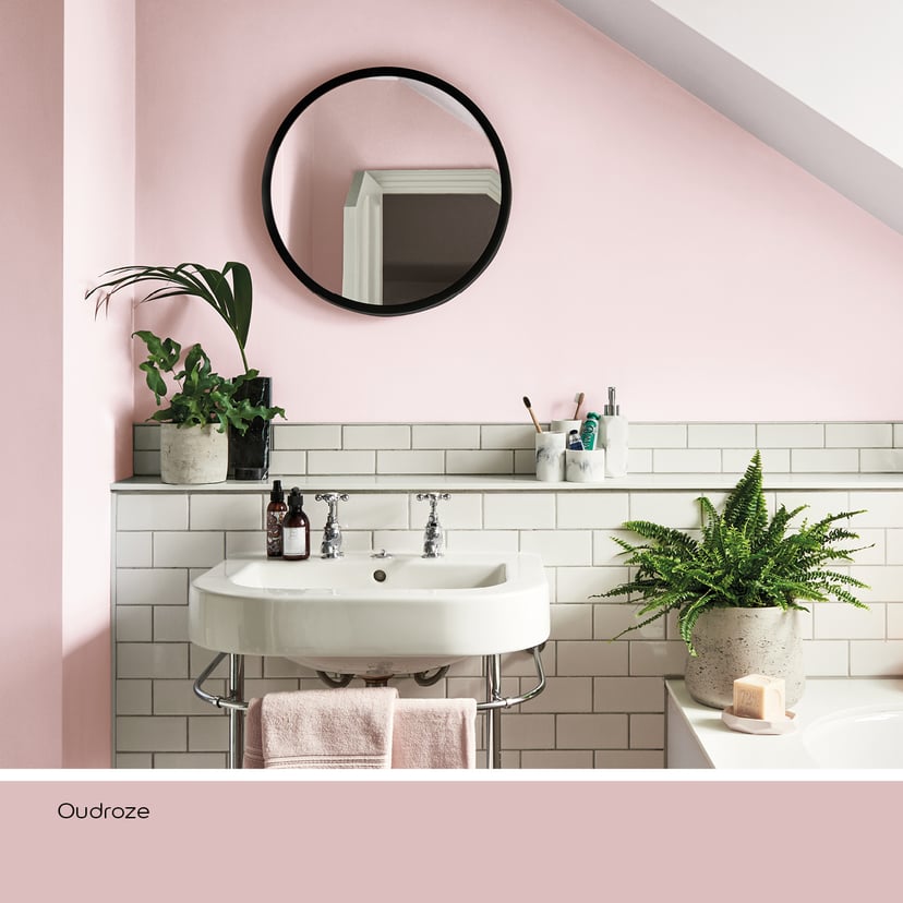 Badkamer met oudroze muur, witte wastafel en groene planten