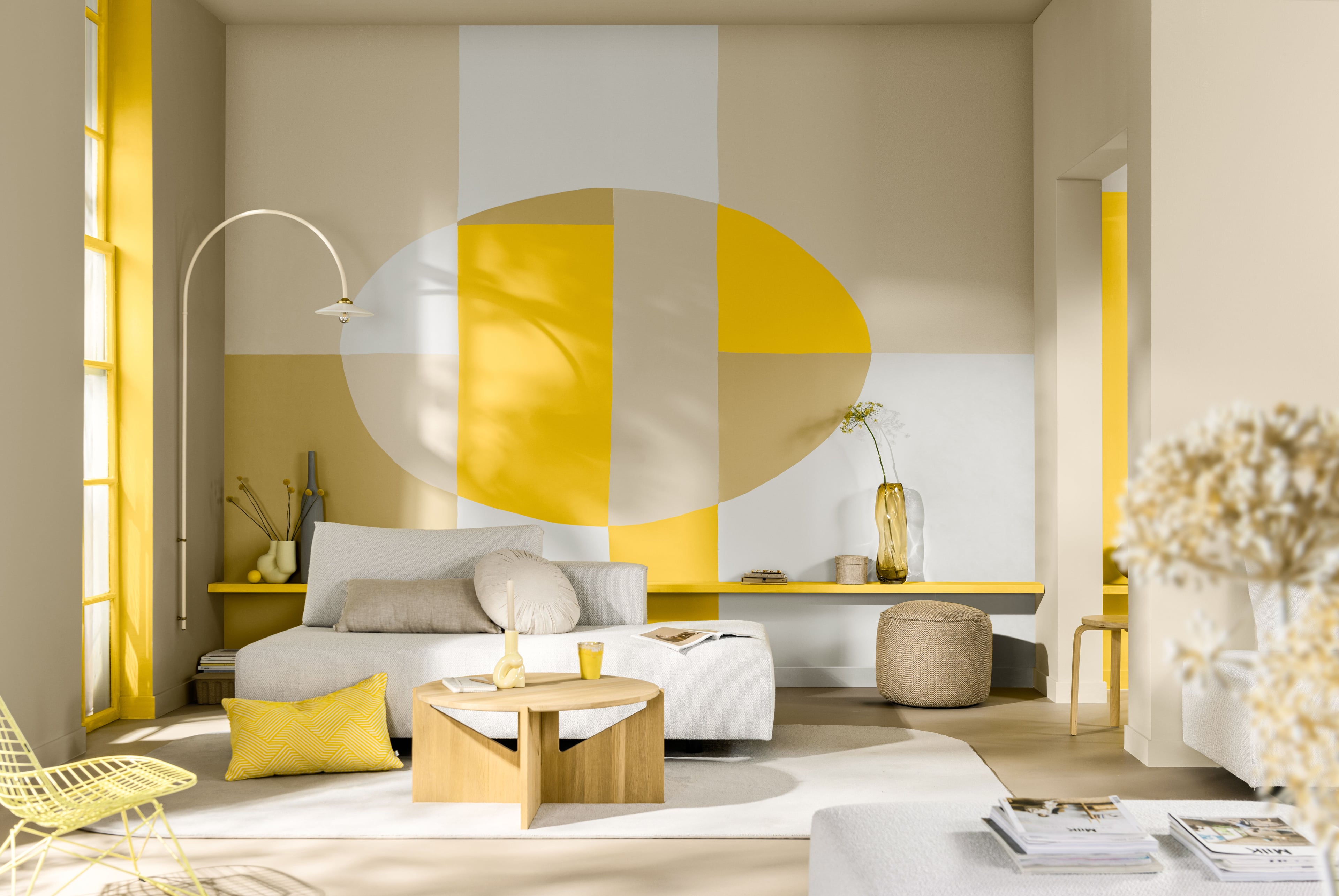 Woonkamer met opvallende geel‑witte geometrische muurschildering.
