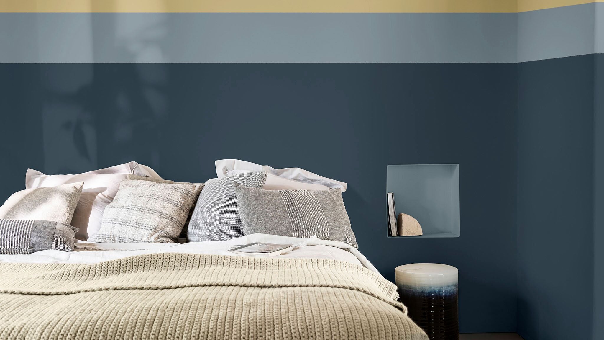 A bedroom with dark blue walls topped with lighter stripes